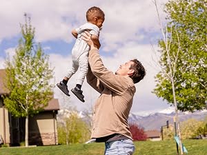 A man lifting his toddler at the park with help from Re-Lyte Energy, clean, no-sugar energy support